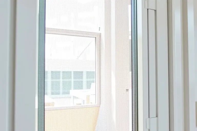 A high-quality close-up of a modern white window frame with a durable mosquito net installed, sunlight filtering through the fine mesh, a clean and bright room visible behind the window, professional factory production aesthetic, photorealistic